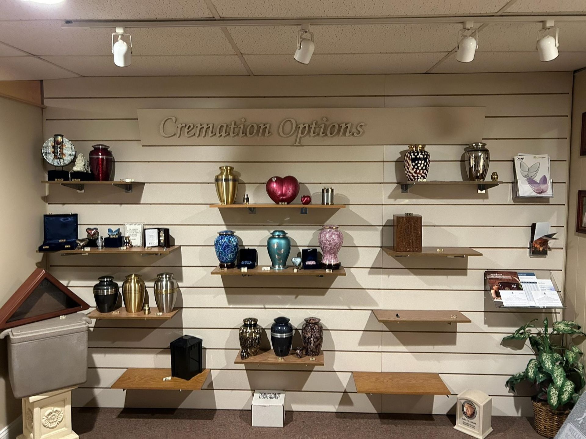 Wall display of colorful cremation urns and keepsakes on shelves in a showroom