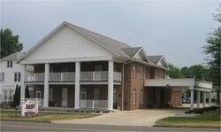 Funeral home with two-story white columns, brick facade, and covered entrance.
