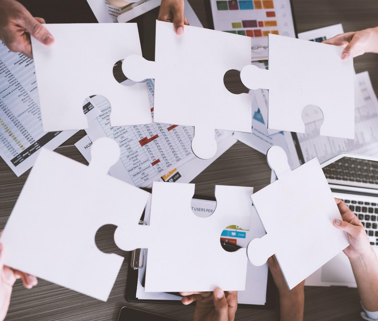 Several corporate executives connecting 6 puzzle pieces 0 depicting the need for Culture in M&A