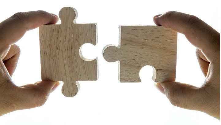 left and right hand each holding a puzzle piece that will soon be connected.