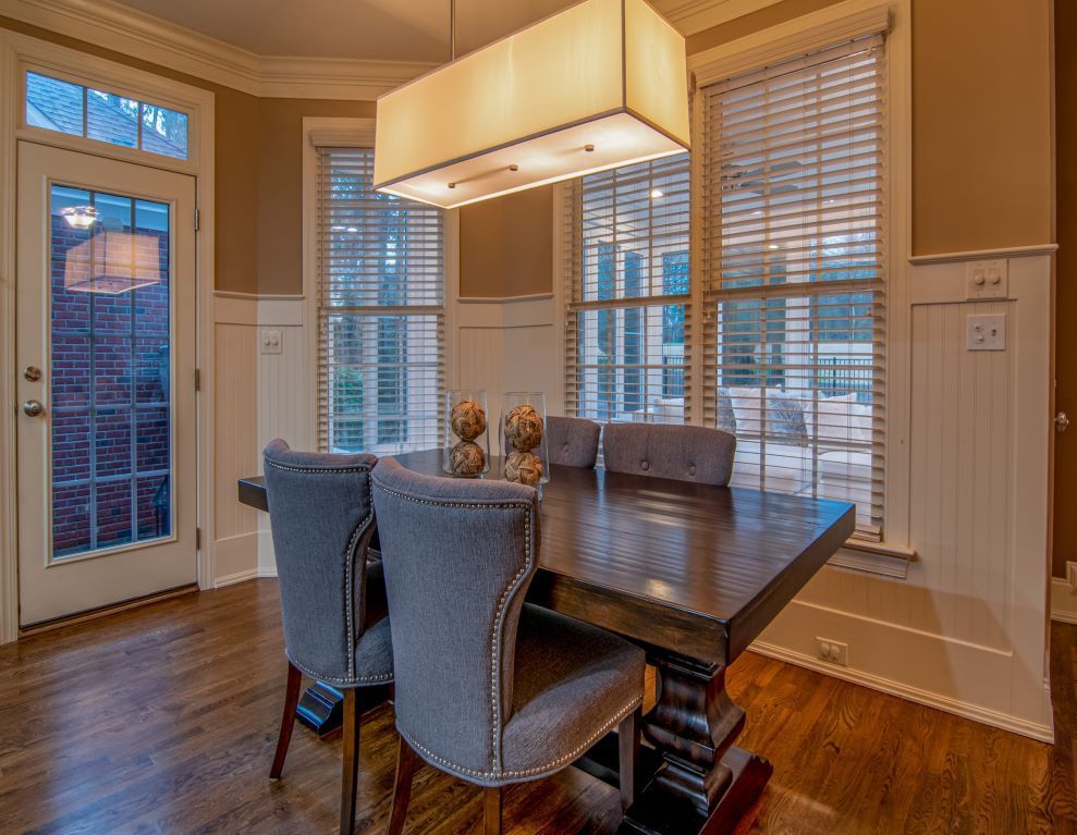 Dining room with dark wood table, gray chairs, large windows, and rectangular light fixture.