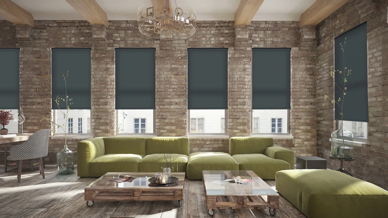 Living room with brick walls, green sofa, blue blinds, and a rustic coffee table.