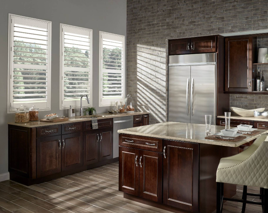 A modern kitchen with dark wood cabinets, stainless steel appliances, and white shutters on the windows.