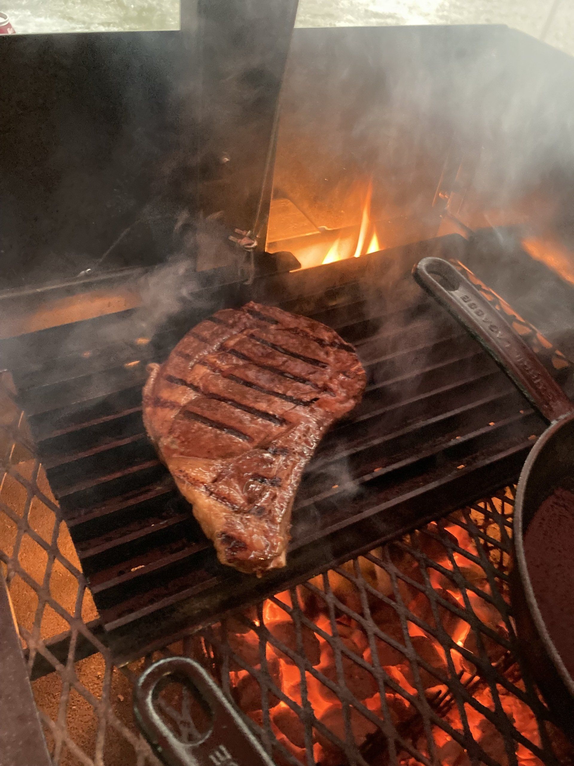 A steak is cooking on a grill with smoke coming out of it