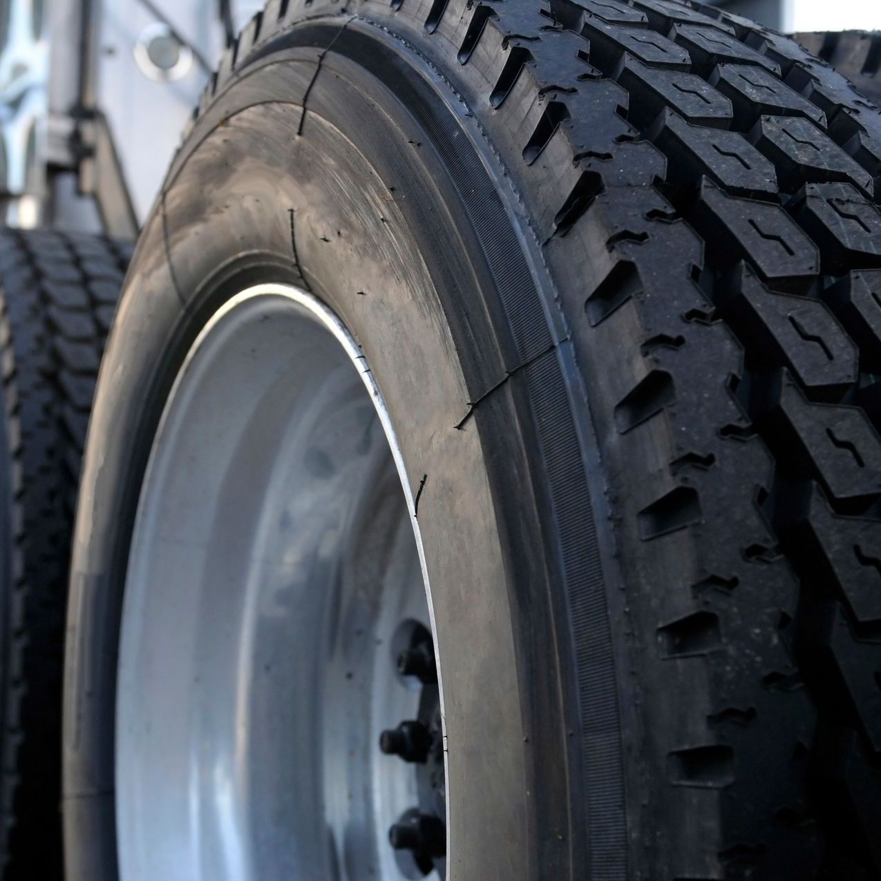 Truck tire on a silver rim, with deep tread.