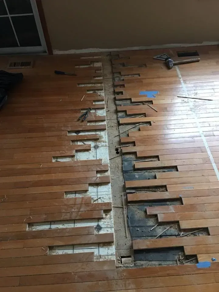 Hardwood floor partially removed, exposing subfloor and joists.