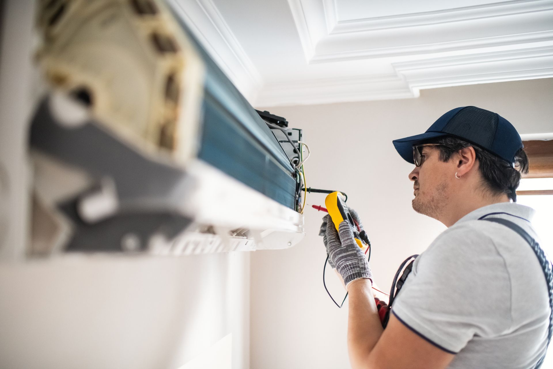 A technician using a multimeter to perform air conditioning repair on a unit at a residential home.