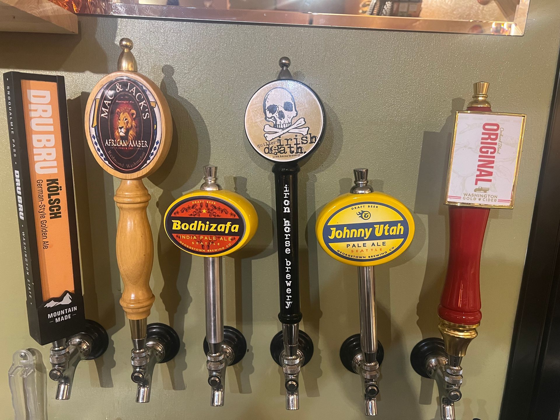 A bunch of beer taps are hanging on a wall