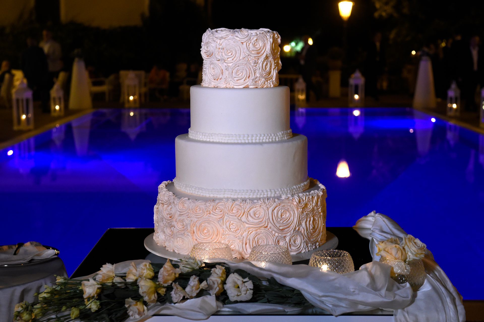 Una torta nuziale è posata su un tavolo davanti a una piscina.