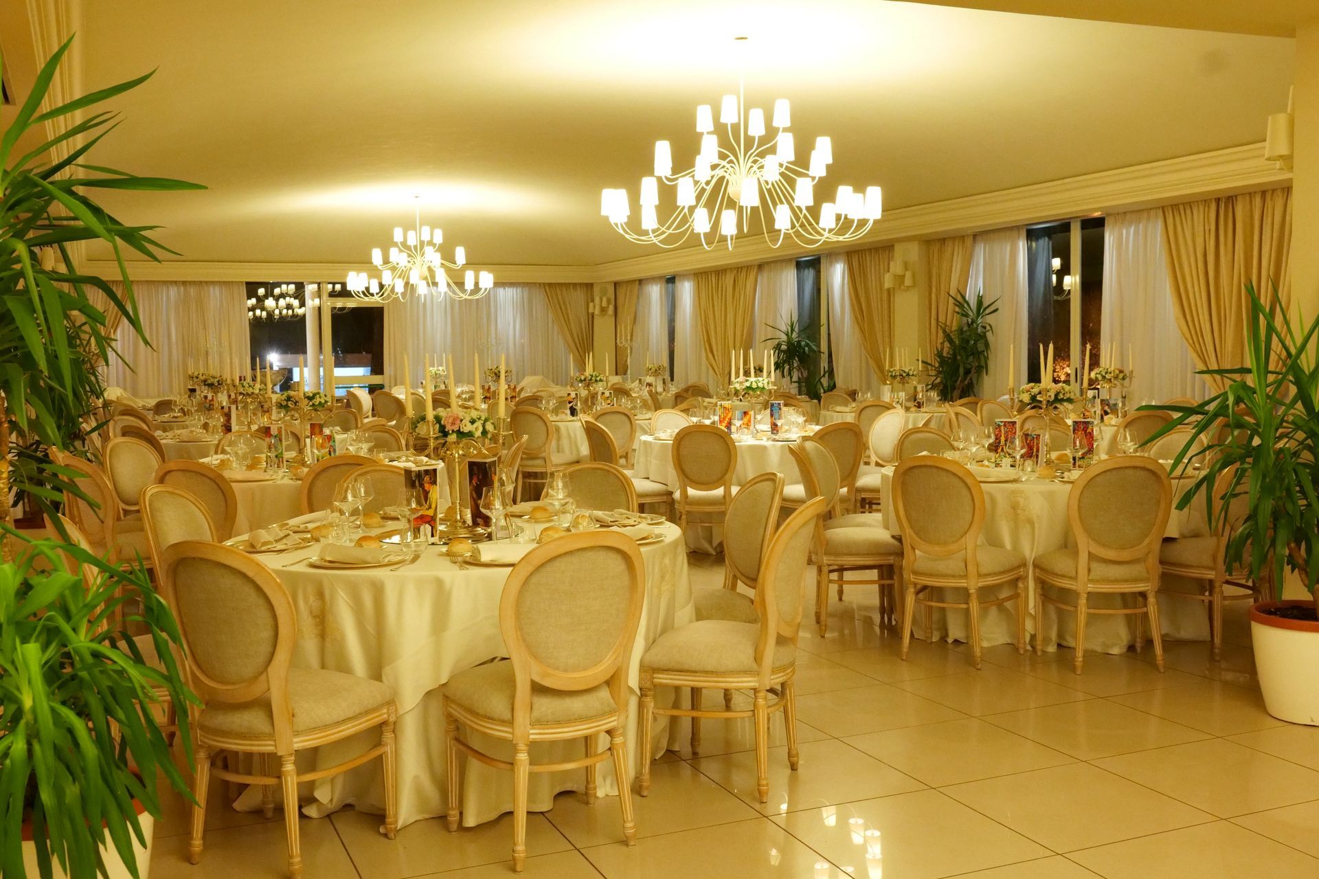 Un'ampia sala con tavoli e sedie allestita per un ricevimento di matrimonio.