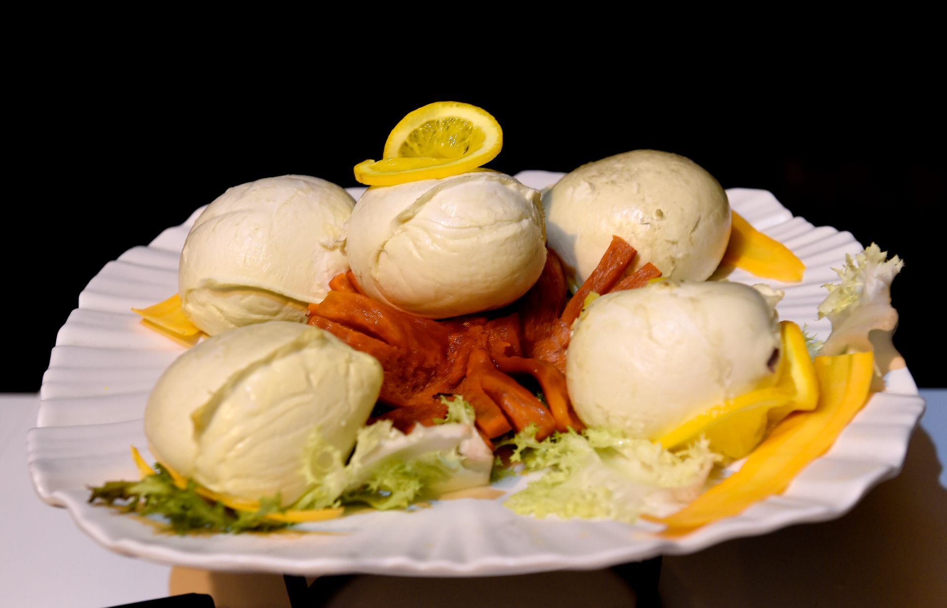 Un piatto bianco condito con uova e verdure e sopra una fetta di limone.