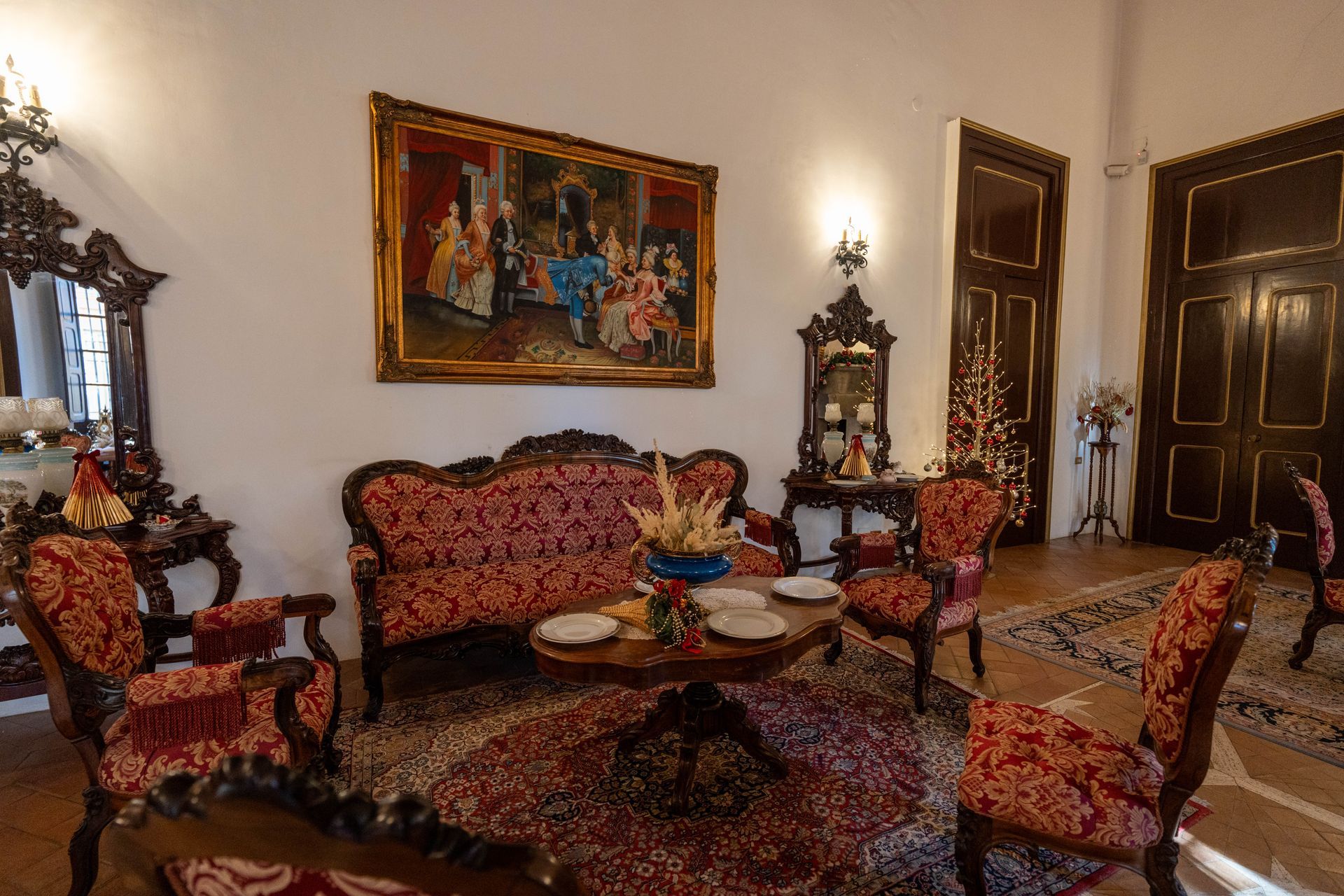 Un soggiorno con un divano, sedie, un tavolo e un quadro sul muro.