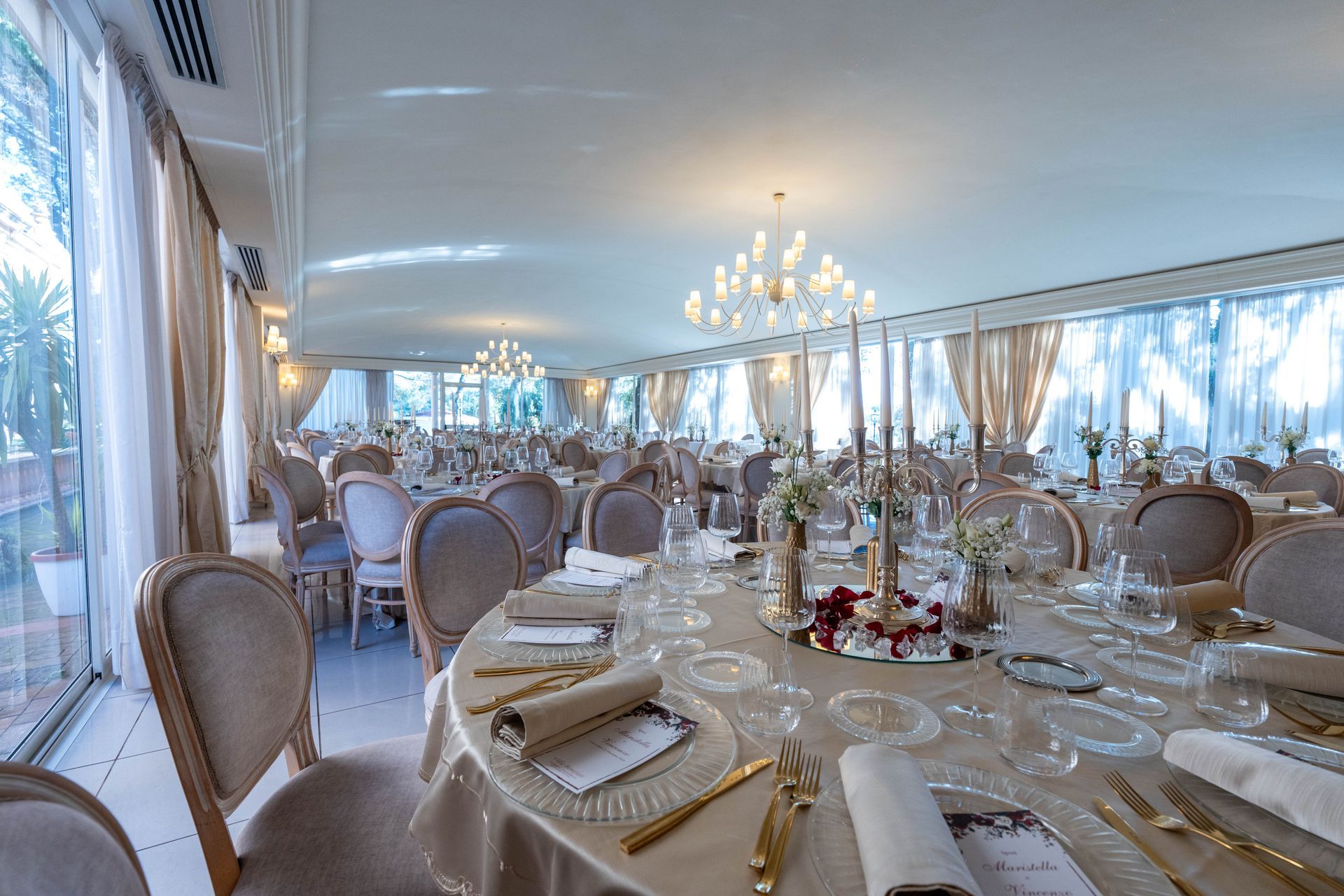 Una grande sala con tavoli e sedie allestita per un ricevimento di nozze.