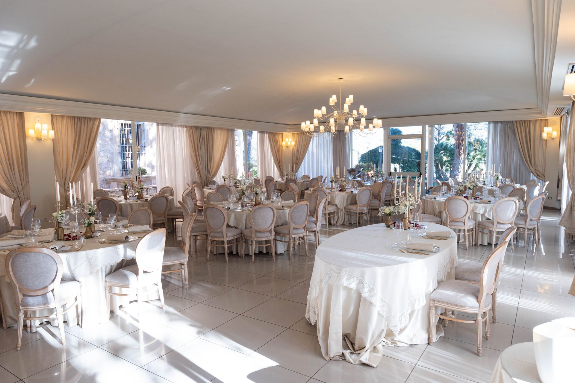 Una grande sala con tavoli e sedie allestita per un ricevimento di nozze.