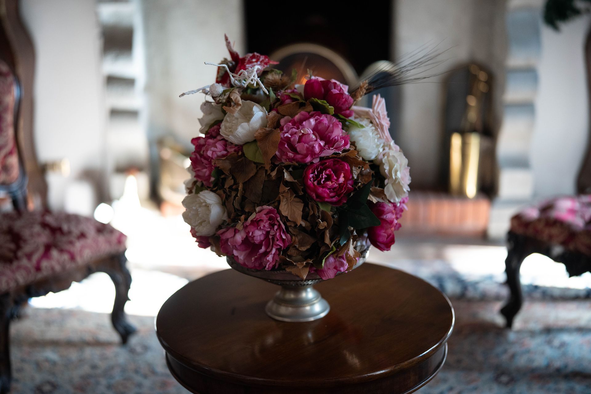 Un vaso pieno di fiori rosa è appoggiato su un tavolo di legno.