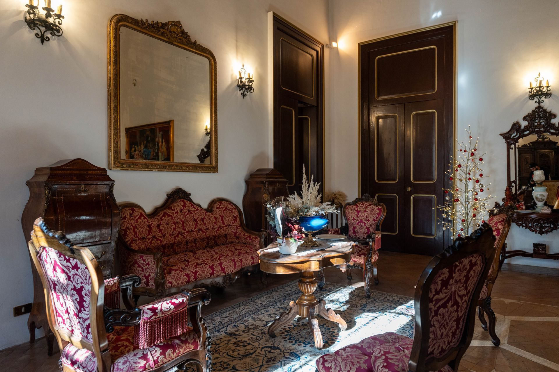 Un soggiorno con un divano, sedie, un tavolo e uno specchio.