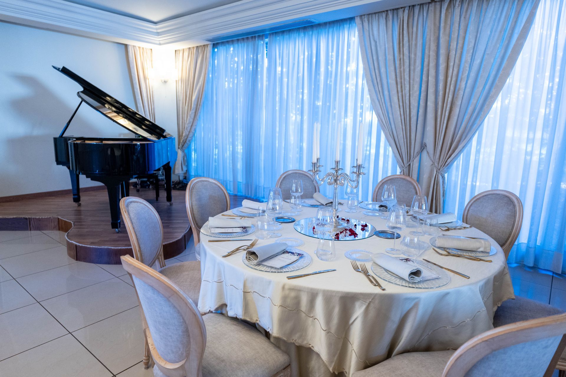 Una sala da pranzo con tavolo e sedie e un pianoforte sullo sfondo.