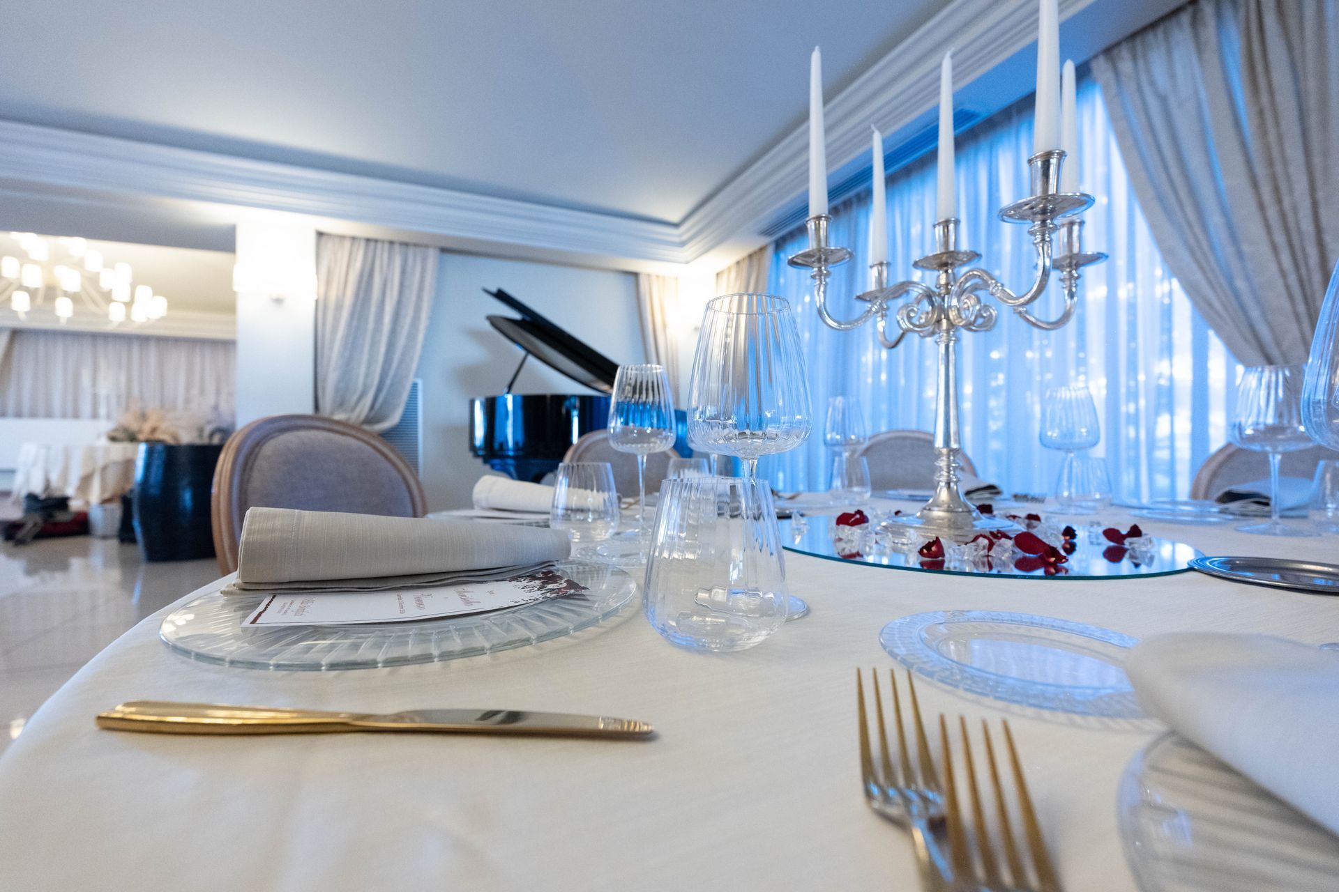Un tavolo apparecchiato per una cena con un pianoforte in sottofondo.