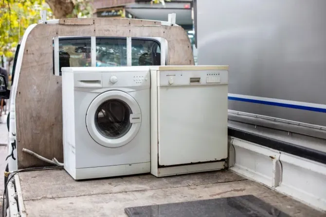 Washing machine and dishwasher on a truck bed beside a road
