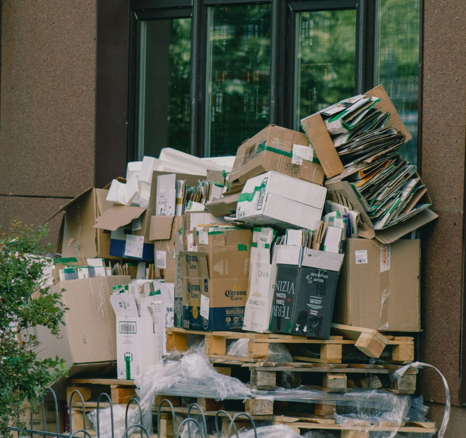 Large pile of cardboard boxes and pallets stacked outside a building window
