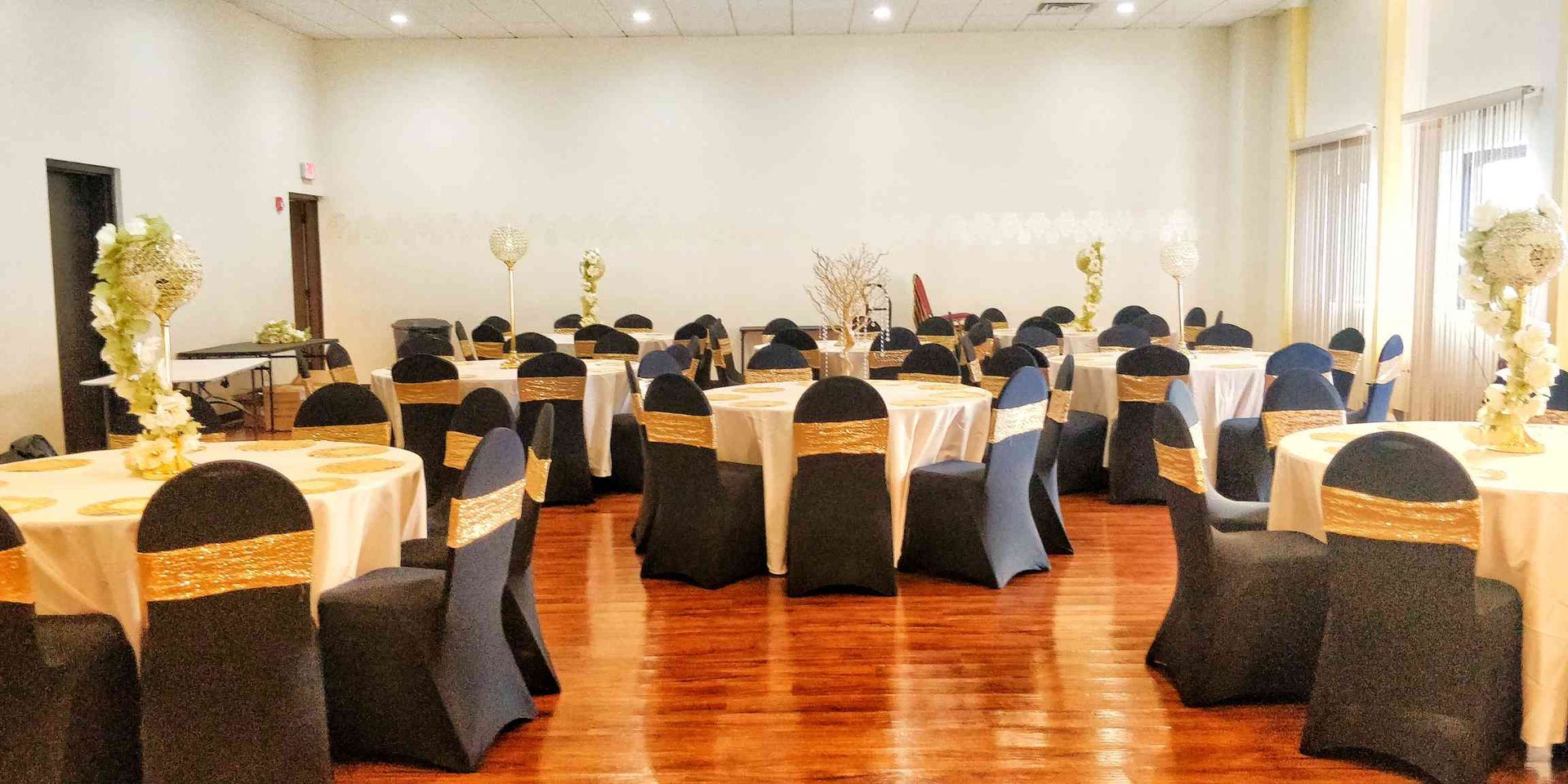 A large room with tables and chairs set up for a wedding reception.