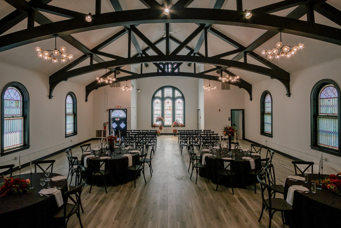 A large room with tables and chairs set up for a wedding reception.