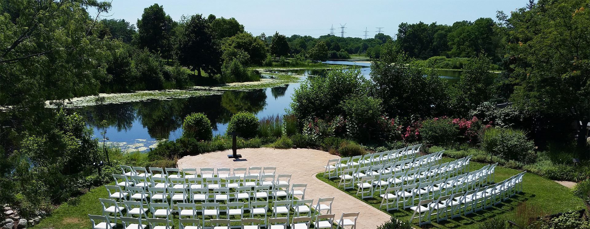 A row of chairs are lined up in front of a lake.
