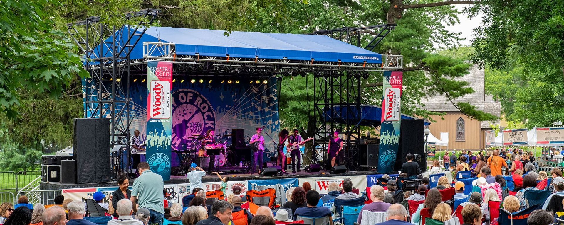 A crowd of people are sitting in front of a stage at a concert.