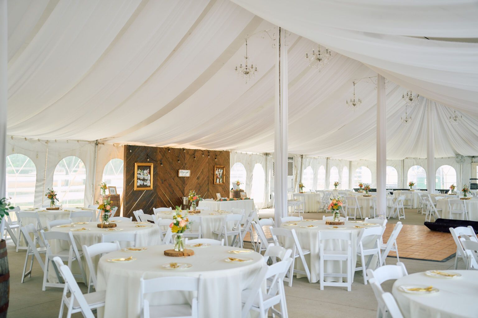 A large tent with tables and chairs set up for a wedding reception.