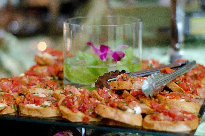A tray of food with tongs and a glass of water on a table.