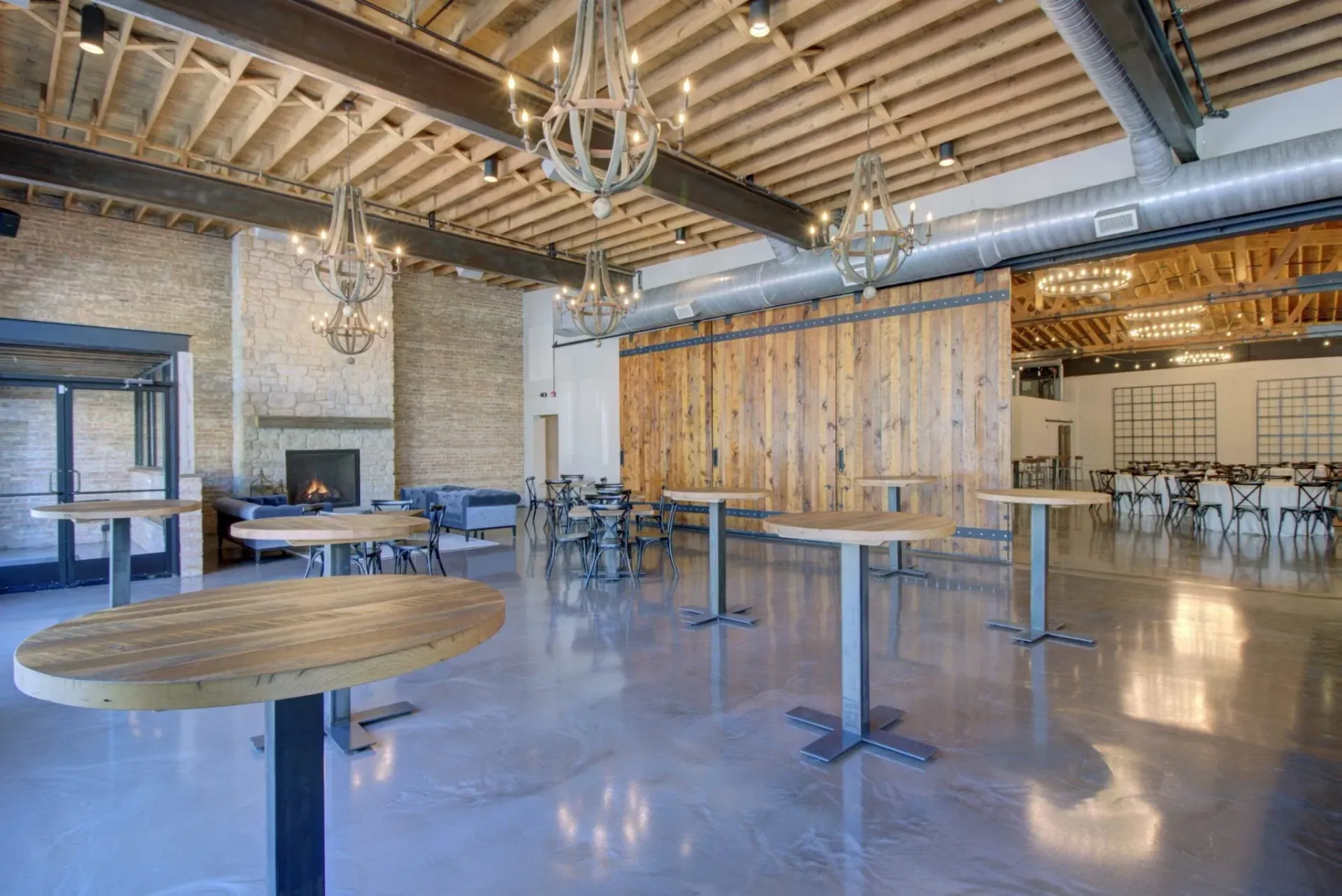 A large room with tables and chairs in it and a fireplace.