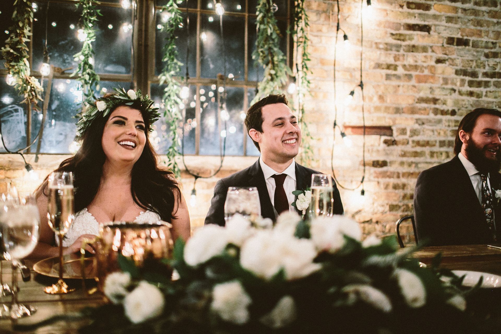 A bride and groom are sitting at a table at a wedding reception.