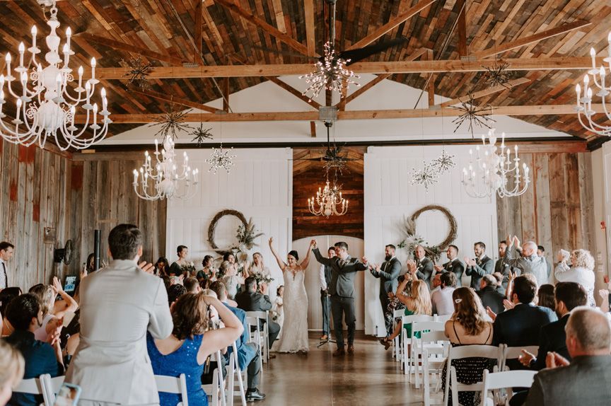 A bride and groom are standing in front of a crowd at their wedding ceremony.