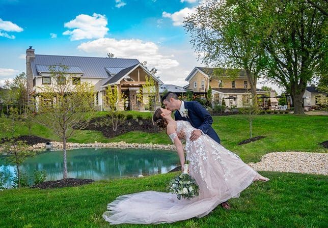 A bride and groom are kissing in front of a house.