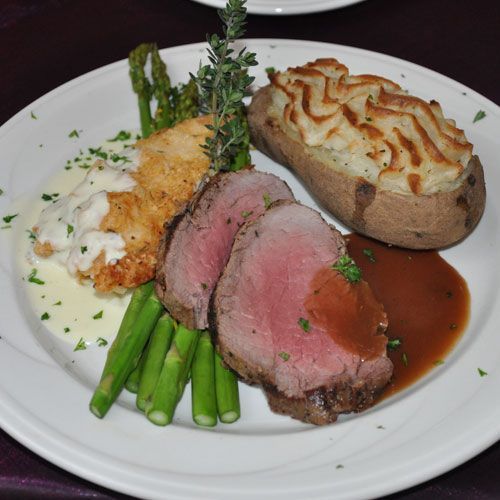 A white plate topped with meat asparagus and mashed potatoes