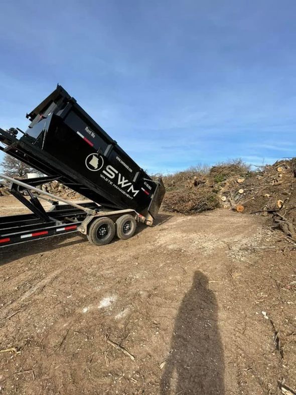 Dump truck tipping a load of dirt at a construction site under a blue sky