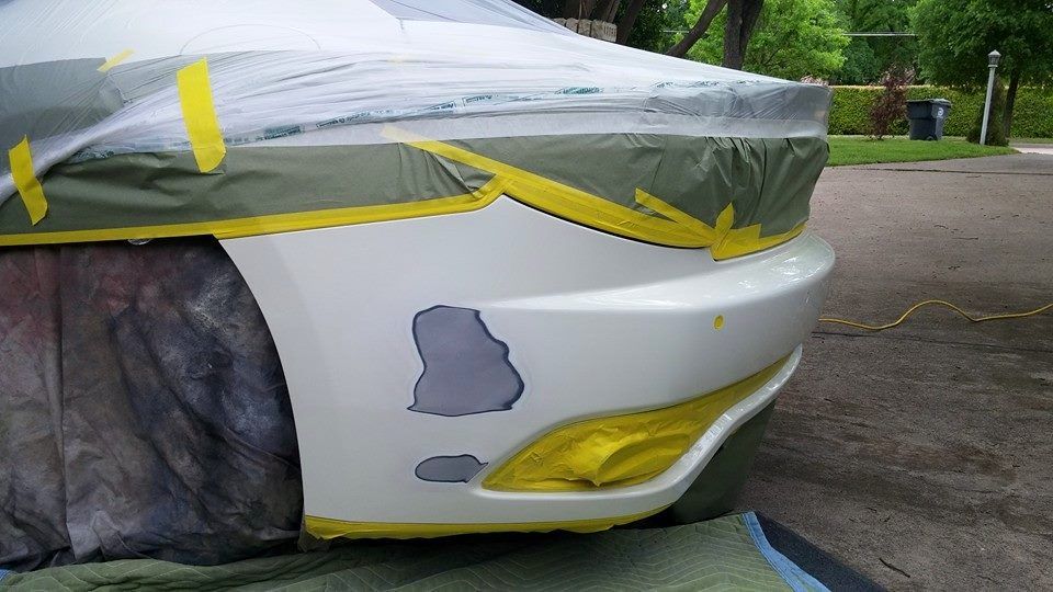 A white car is being painted with yellow tape