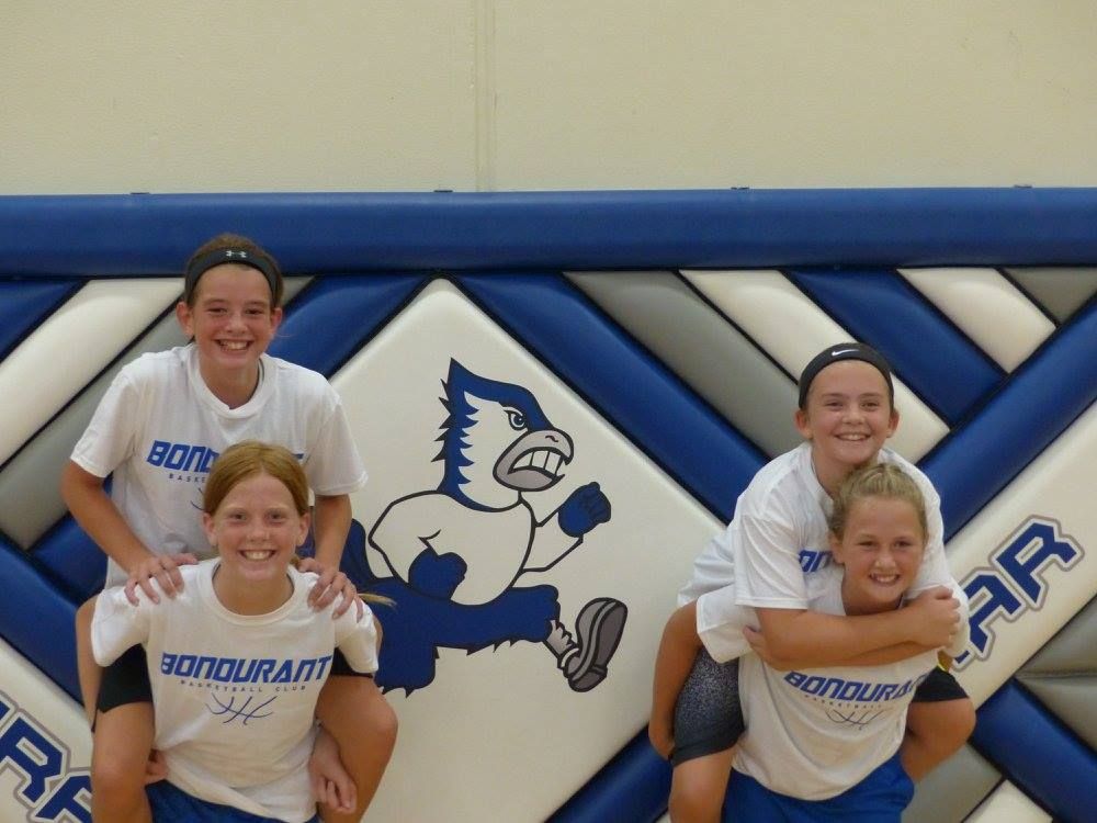Four people in white shirts pose in front of a blue-and-white inflatable sports mascot backdrop.