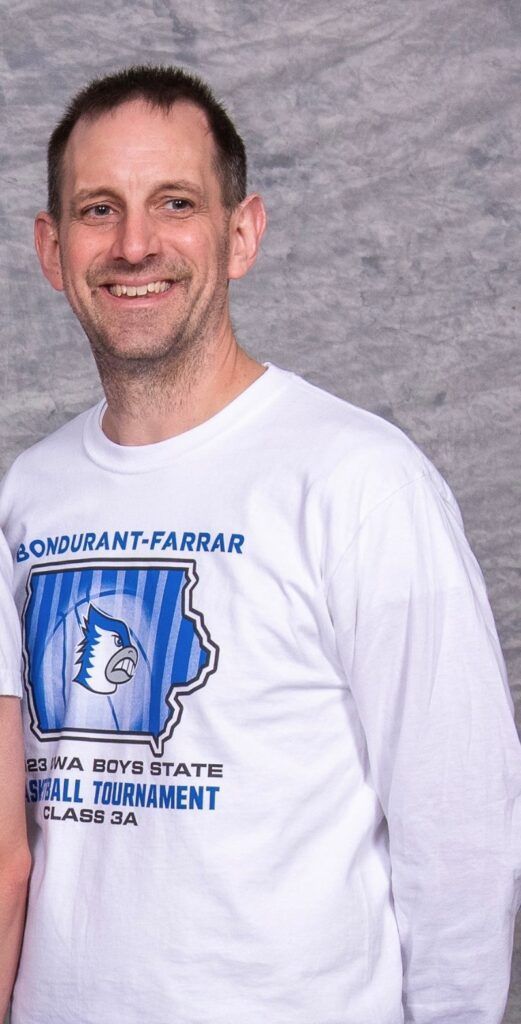 Smiling man in a white long-sleeve T-shirt against a gray backdrop