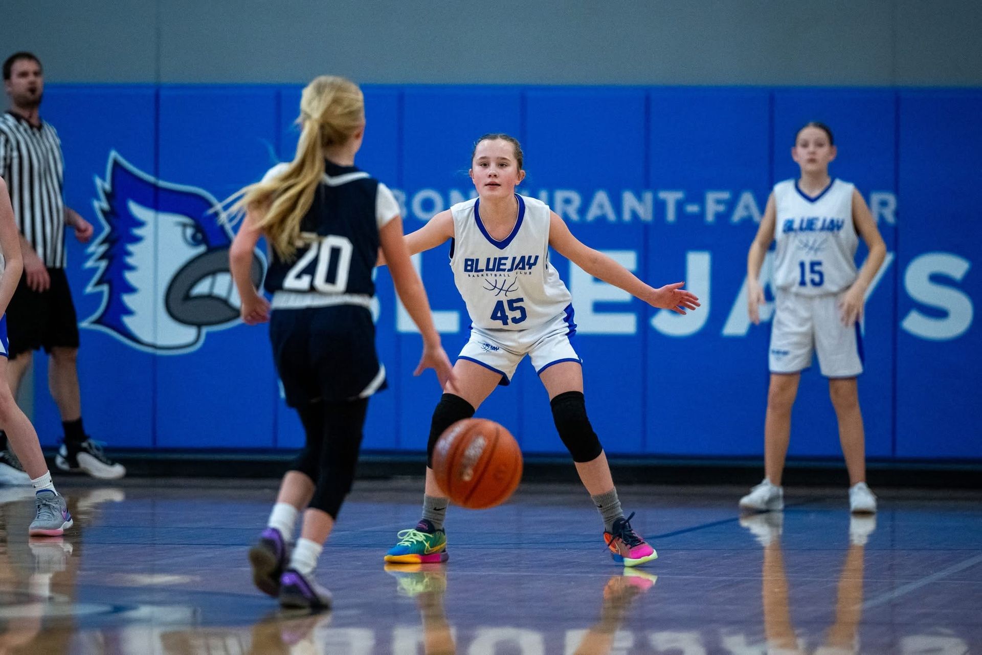 Smiling girls in white basketball jerseys posing in a school hallway after a game