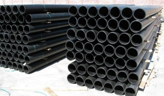 Pilas de tubos de plástico negro, posiblemente para construcción o drenaje.