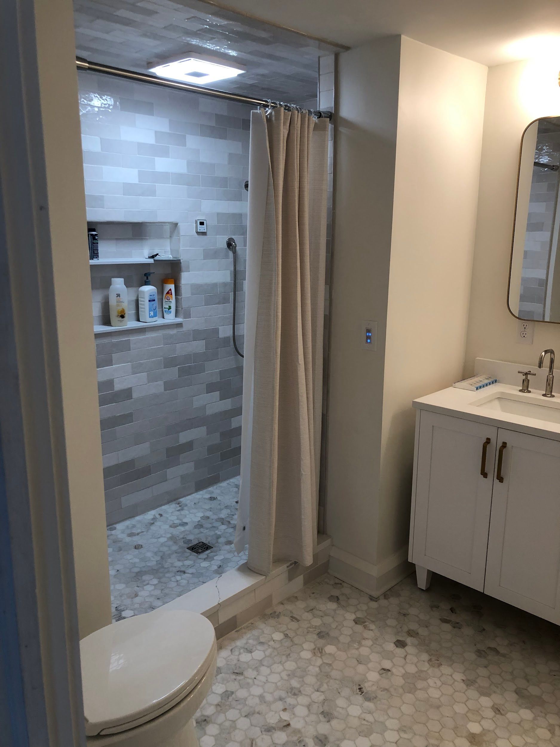 A bathroom with a toilet , sink and shower.