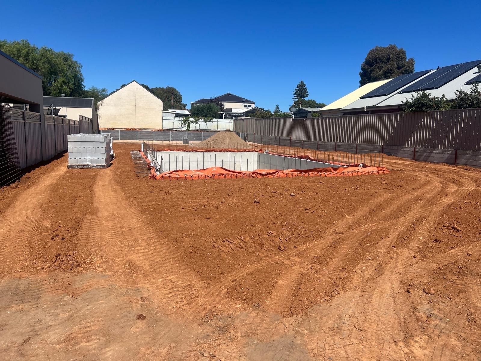 A dirt field with a fence and a house in the background