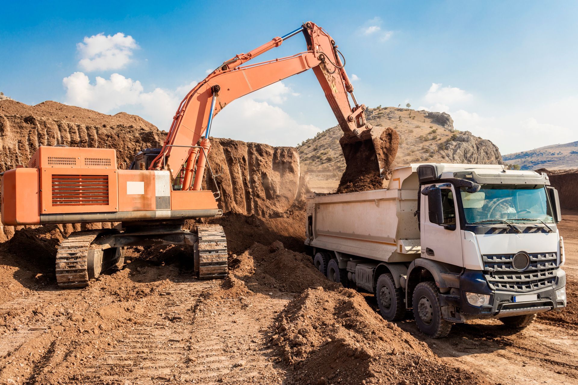 An excavator is loading dirt into a dump truck at a construction site.