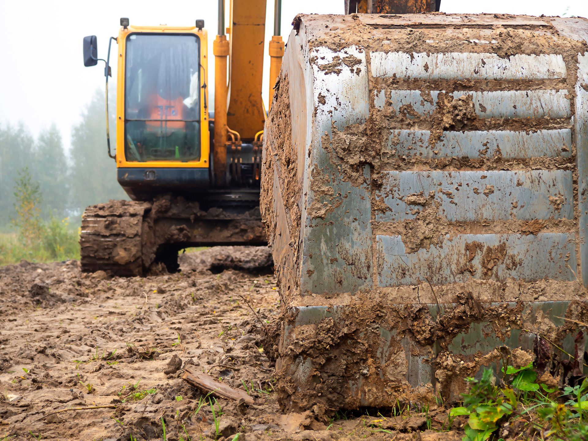 A yellow excavator is digging a hole in the dirt on a construction site.