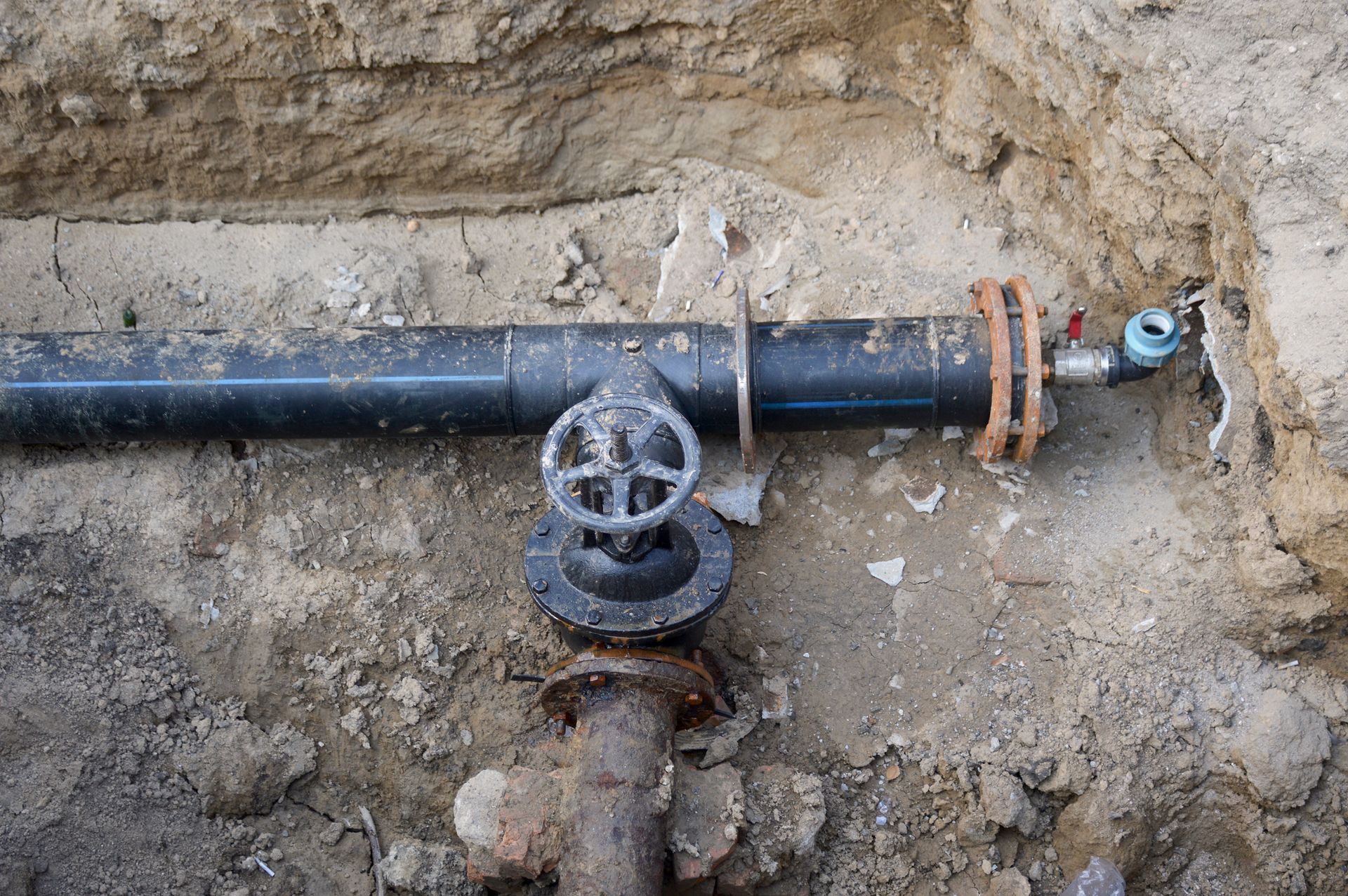 A pipe with a valve on it is sitting in the dirt.