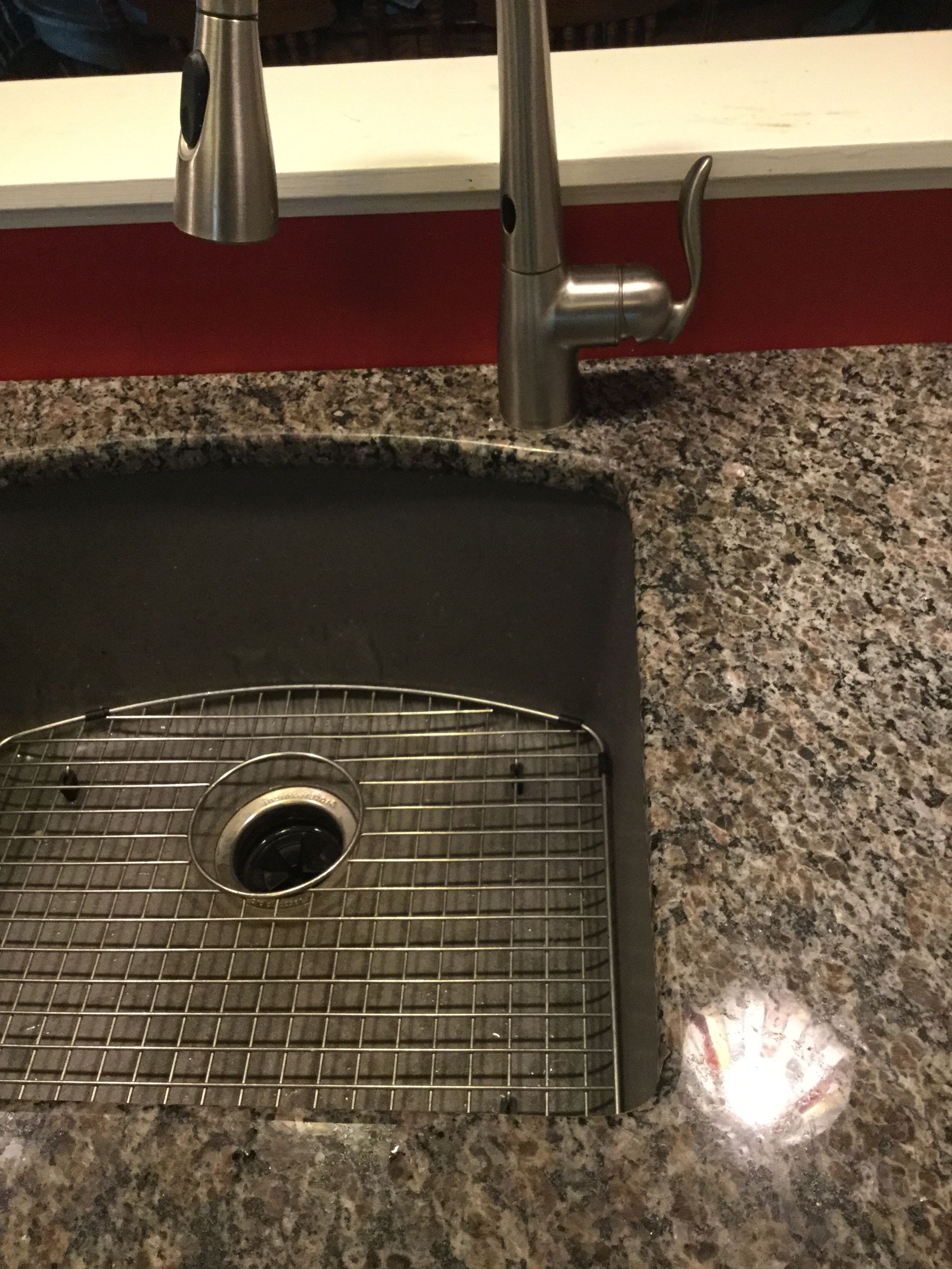 Stainless steel kitchen sink with faucet, drainboard, and black countertop.