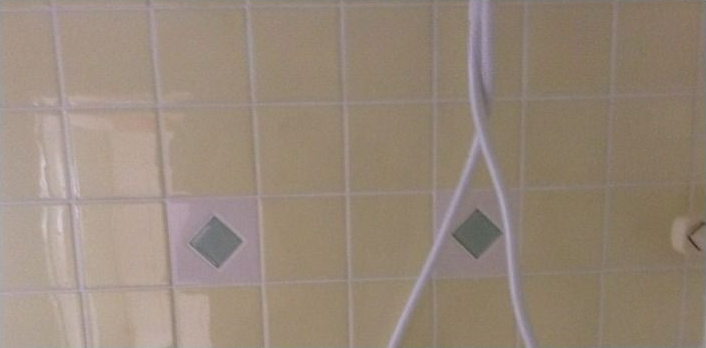 Yellow tiled wall with two green diamond accents and hanging white cords