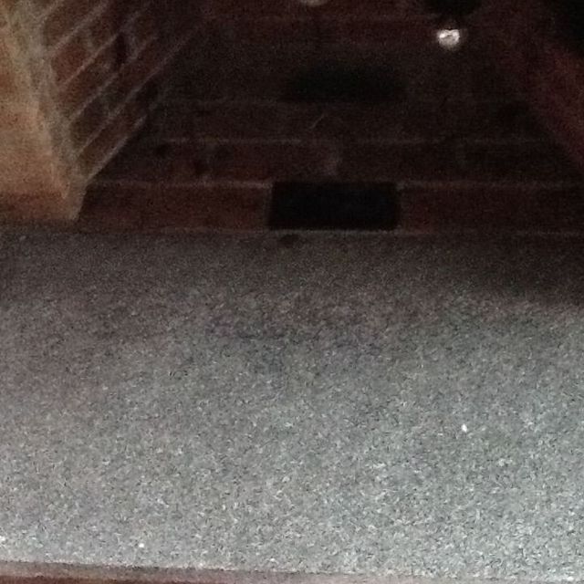 Dark brick-walled tunnel with a gray floor and a small bright light at the far end