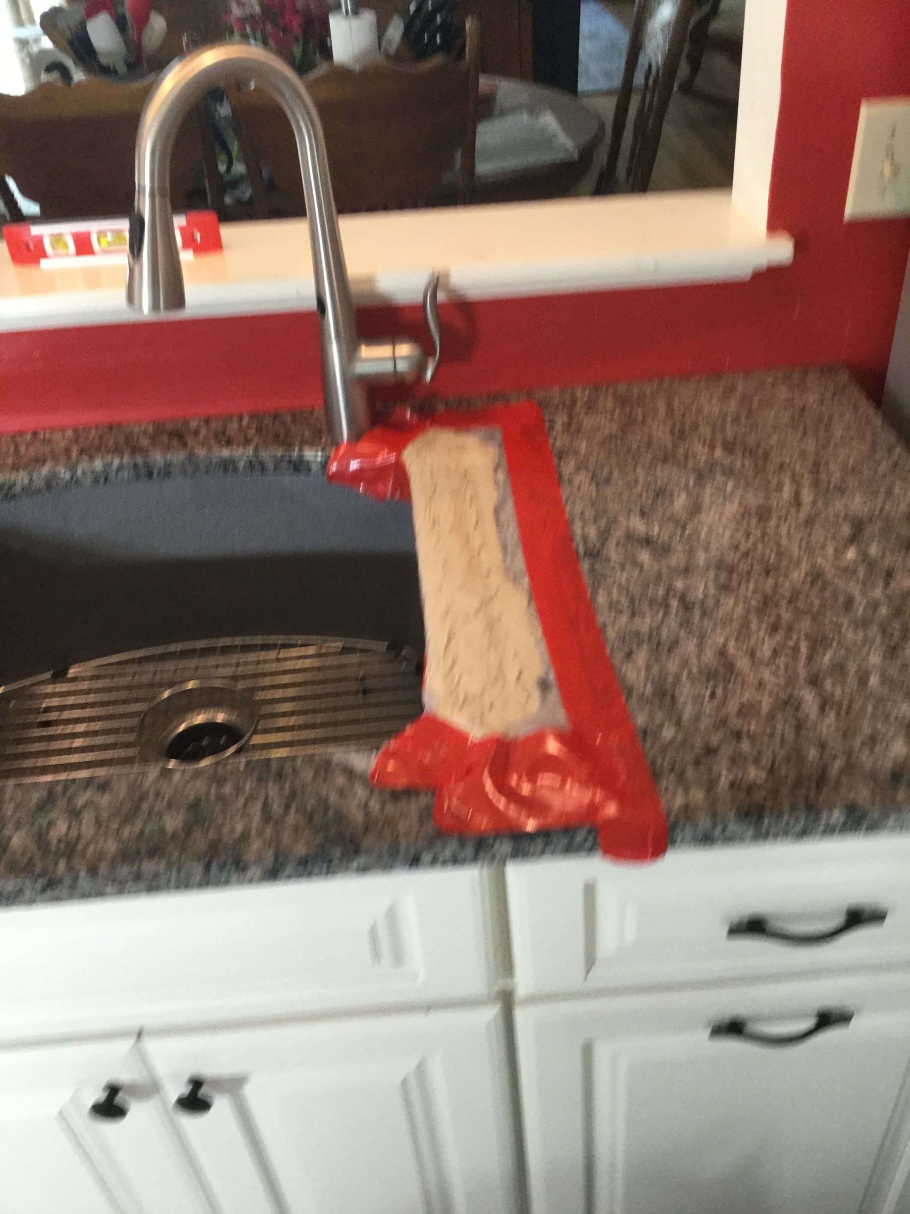 Kitchen sink with a red-brown bread loaf or cake on a cutting board by the faucet